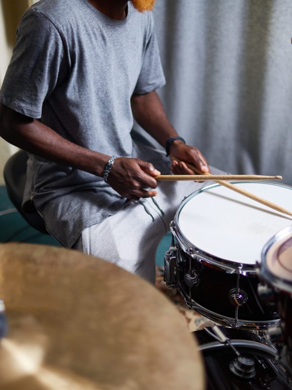 Young man with drumsticks recording his music in home studio